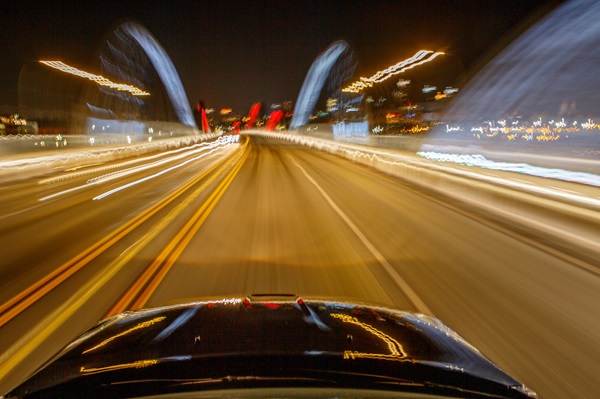 POV from the driver seat of a car going fast down the highway at night, with everything blurry to indicate impaired driving.